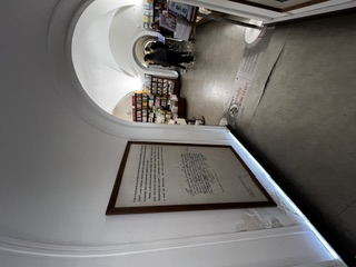 The arched entrance of a Lisbon bookstore with a framed poem on the white wall.