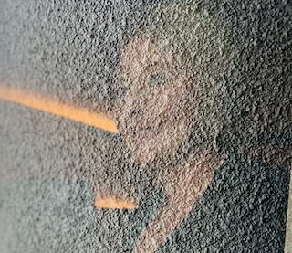 A slant of orange light falling across a rough concrete wall.