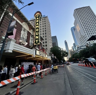 The Paramount Theatre marquee on Congress Avenue in Austin with a line of people waiting outside.