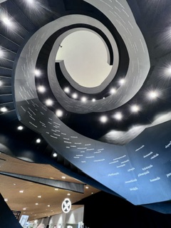 A spiral ceiling of curved balconies and pin lights winding upward toward a bright oculus.